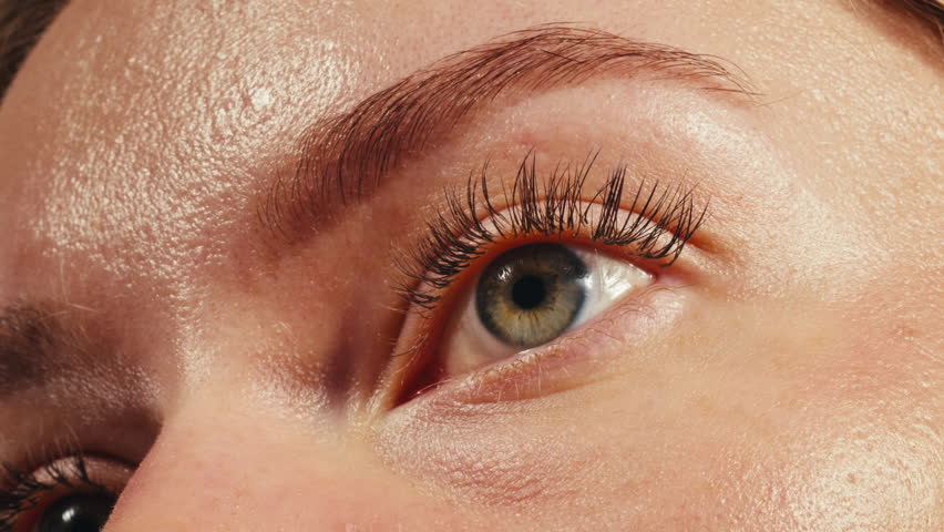 Close-up womans blinking eye with long eyelash and contact lens. Beauty make up of green eye with neon light.