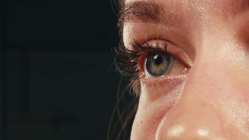 Close-up womans blinking eye with long eyelash and contact lens. Beauty make up of green eye with neon light.