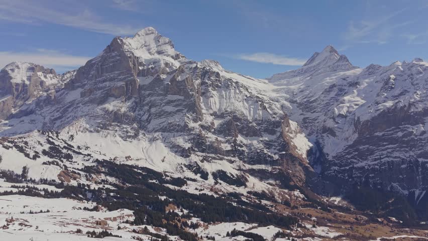 Aerial view of the summit station Grindelwald First, surrounded by massive snowy mountains.