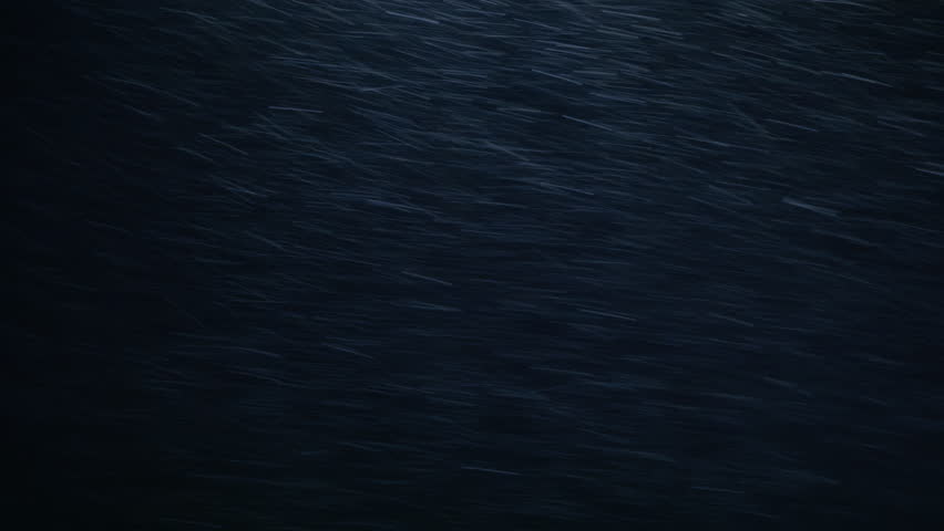 Heavy snow streaks rapidly across a dark, stormy background, illuminated by a subtle light source. Ideal for weather, abstract, dramatic, or atmospheric scenes, conveying intensity and motion