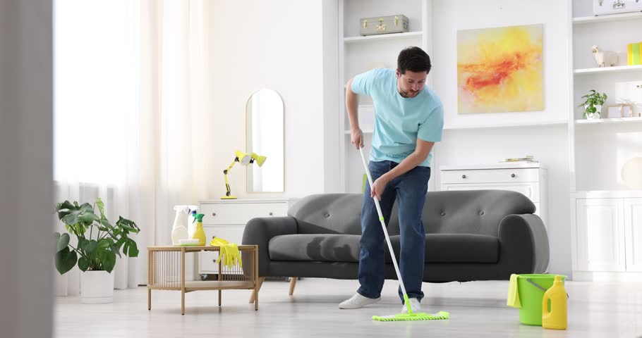 Spring cleaning. Man tidying up floor with mop at home