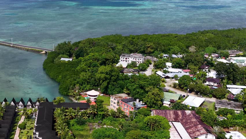 High angle drone shot captures a tropical resort nestled along turquoise waters and lush greenery