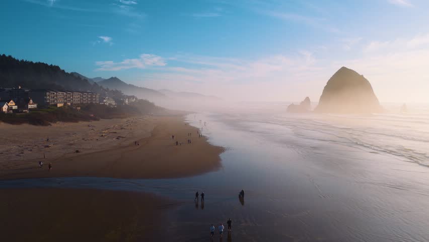 Drone footage capturing late evening Cannon Beach, Haystack Rock, and coastal waves. Ideal for travel and landscape media.
