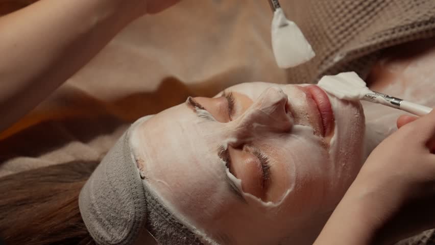 Relaxing spa facial treatment with soothing white mask application on woman face, highlighting professional skincare, pampering, tranquility, and wellness therapy