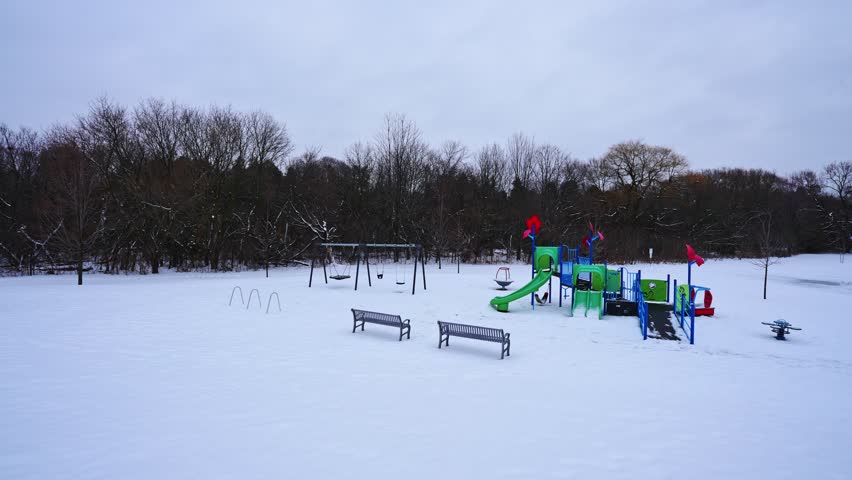 Playground for Children Covered in Winter Snow at Courtice Florell Drive Park, Panning Shot.