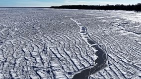 Wide frozen sea covered in wind-sculpted snow textures and crack lines, stretching to the horizon under clear blue winter sky. Copy space. - Powered by Shutterstock - Get 15% off with code: PIKWIZARD15
