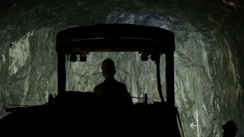 Miner operating a cargo transport vehicle in an underground mine, illustrating mining operations, industrial work, and heavy machinery handling.