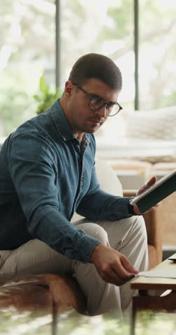 Document, tablet and man in home for remote work, budget approval or accounting with audit. Technology, living room or freelance accountant with paperwork for financial report, reading or bookkeeping