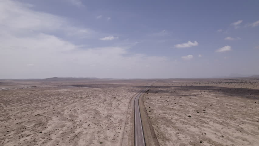 An empty highway cutting through the stark west Texas desert, slow aerial view
