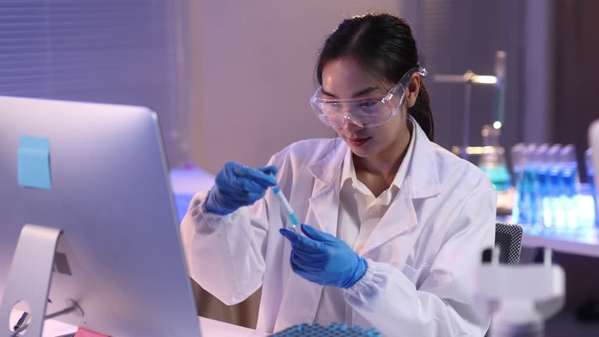 Scientist working with test tube in laboratory. Scientist in a lab coat and safety glasses carefully handles a test tube at a desk in a laboratory, experimentation in a controlled environment.