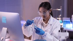 Scientist working with test tube in laboratory. Scientist in a lab coat and safety glasses carefully handles a test tube at a desk in a laboratory, experimentation in a controlled environment. - Powered by Shutterstock - Get 15% off with code: PIKWIZARD15