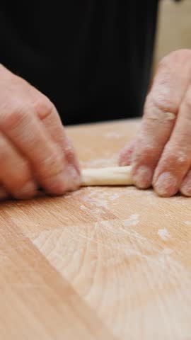 A man prepares typical Apulian pasta on a wooden cutting board
