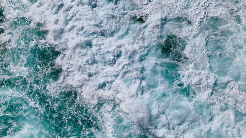 Natural ocean background with intense wave movement and sea foam, top down view