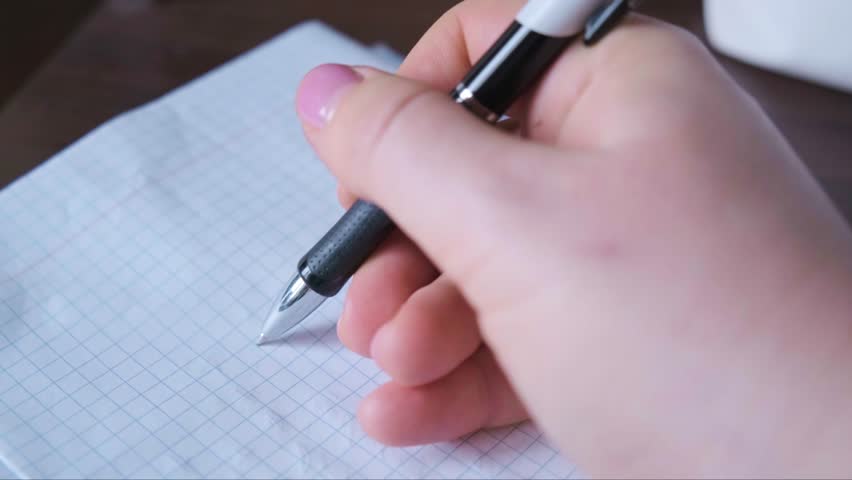 Close up of hand writing on paper with ballpoint pen testing pen before use