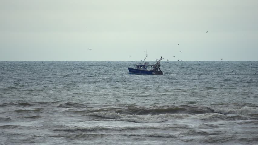 Fishing boat moves off the Opal Coast in France as gulls follow.