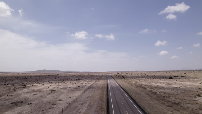 An empty highway cutting through the stark west Texas desert, aerial view