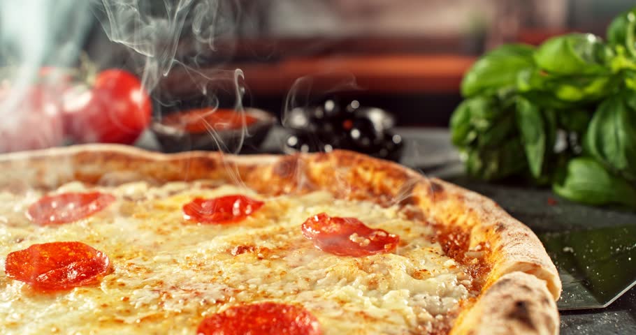 Super slow motion footage (1000 fps) of a pizza slice being lifted with perfectly melted, stretchy cheese. Rich textures of crust, salami, tomato and fresh basil in cinematic light.