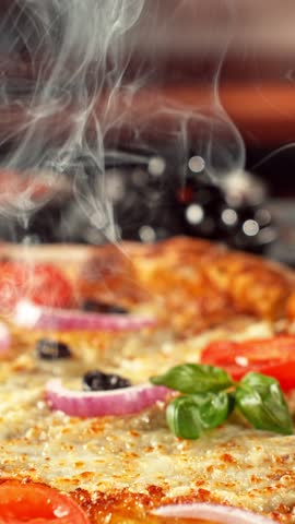 Super slow motion footage (1000 fps) of a pizza slice being lifted with perfectly melted, stretchy cheese. Rich textures of crust, salami, tomato and fresh basil in cinematic light.