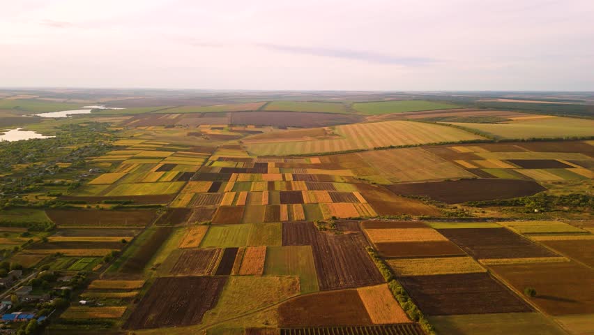 Aerial view of agricultural countryside with fields and rural horizon. Drone aerial landscape of wide agricultural countryside with cultivated fields stretching toward distant horizon.