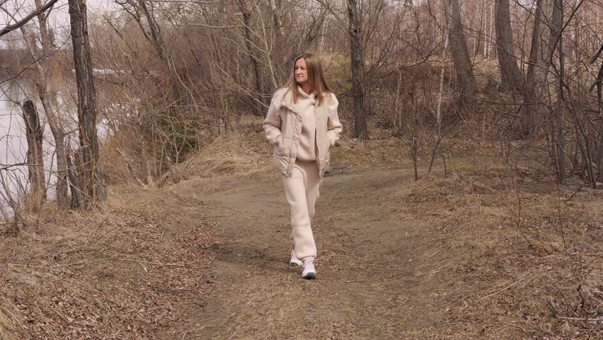 Active lifestyle young woman walking along forest path early spring casual outfit forest atmosphere forest connection with nature healthy habits freedom movement outdoor recreation mindful walk