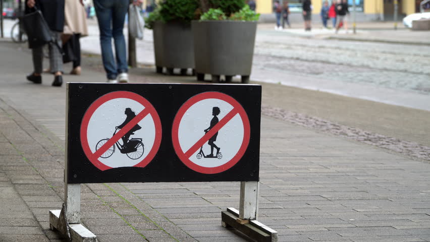 No cycling or scooter sign on a city pedestrian sidewalk captured with shallow depth of field, urban traffic regulation and micro mobility safety concept.