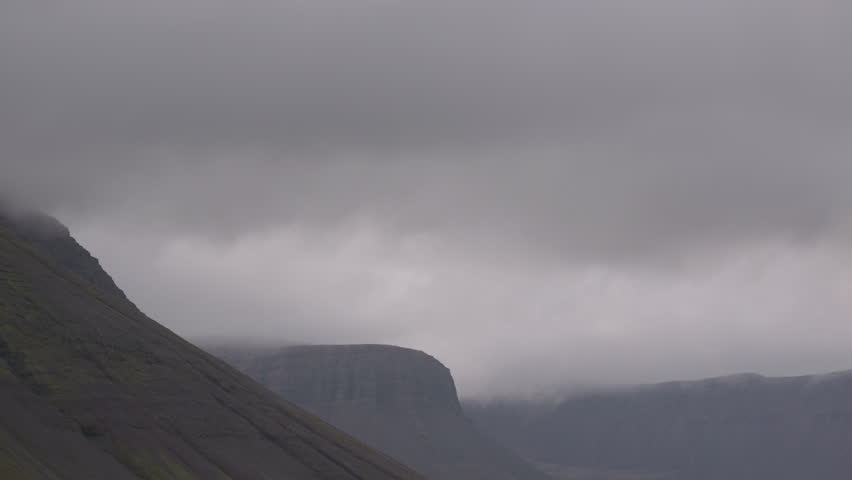 Dense clouds moving over mountain tops in the Icelandic fjords near Isafjordur, Iceland