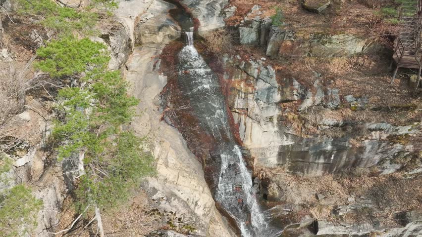 Aerial drone shot of the majestic Suok Waterfall surrounded by lush forest in Goesan, South Korea