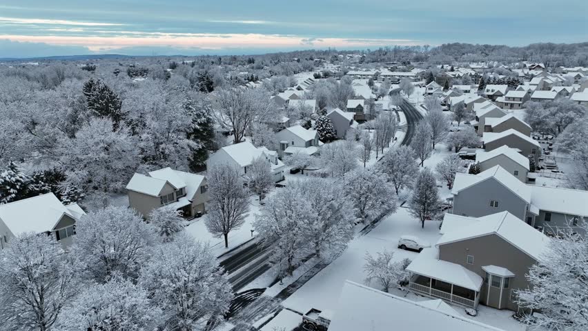 Aerial approaching shot of typical American suburban houses, in contemporary architecture design. Snowy Christmas Day in winter season. Peaceful and quiet neighborhood of Pennsylvania.