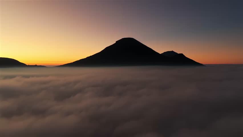 Mountain Silhouette Above Sea of Clouds at Sunrise