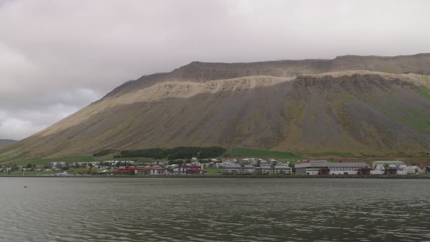 The shoreline of Isafjordur, Iceland, calm waters and thick clouds over the mountains