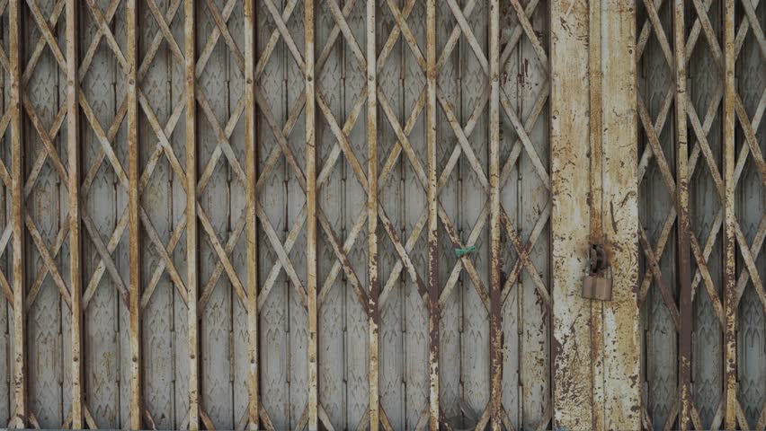 Old metal folding gate with rusty surface and geometric pattern. Industrial detail.