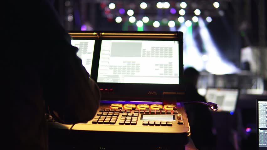 Lighting technician programming a professional control desk during a live music concert or show