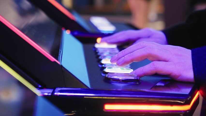 A man is playing slots machine and roulette or poker, gambling in casino close up, game machine in cafe or hotel lobby. Playing betting game.