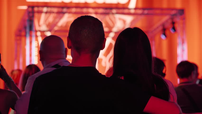 Couple embracing while watching a live concert with vibrant stage lights