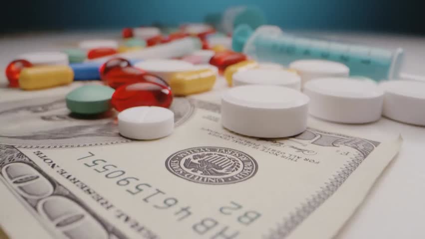 Close-up of pills and syringes on US dollar bills, highlighting healthcare costs, pharmaceutical industry, and the economics of medicine