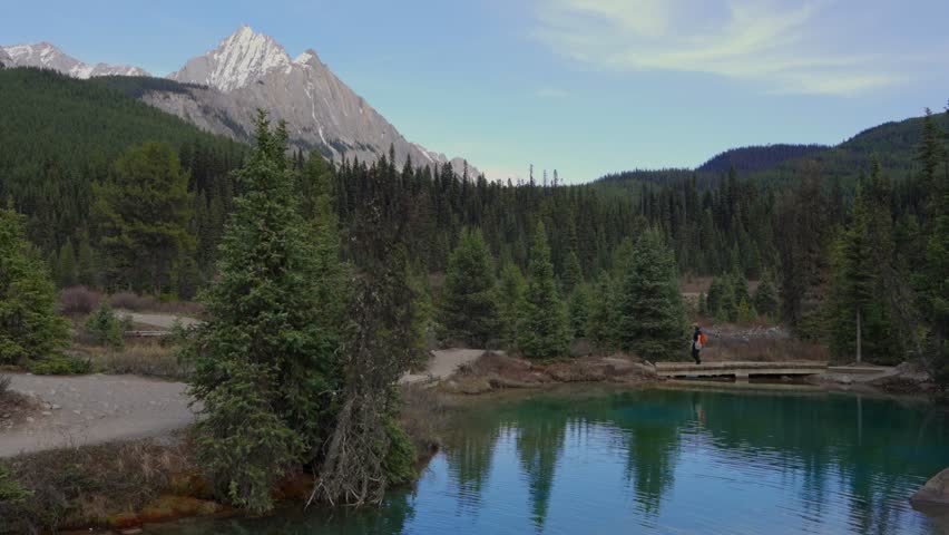 Woman hiking bridge over Ink Pot spring in Jasper National Park