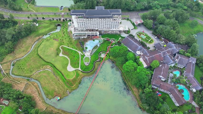 Aerial view of luxury hotel resort with swimming pools and lake surrounded by green landscape