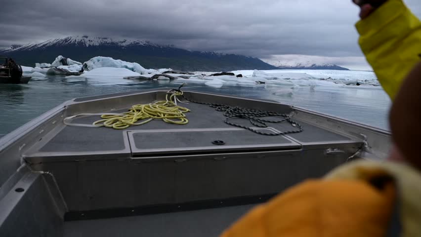 Slow motion cinematic handheld POV footage of a small boat tour navigating through ice chunks and people watching icebergs on Matanuska Glacier in Alaska.  Ideal for dramatic, adventure, relaxing, travel, outdoor, and glacier-themed projects. 