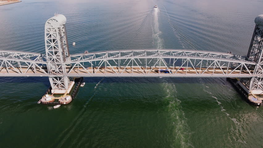 Aerial drone view of the Marine Parkway Bridge connecting Brooklyn and Queens over calm water with sandy shoreline and coastal landscape, filmed in ProRes 422HQ.
