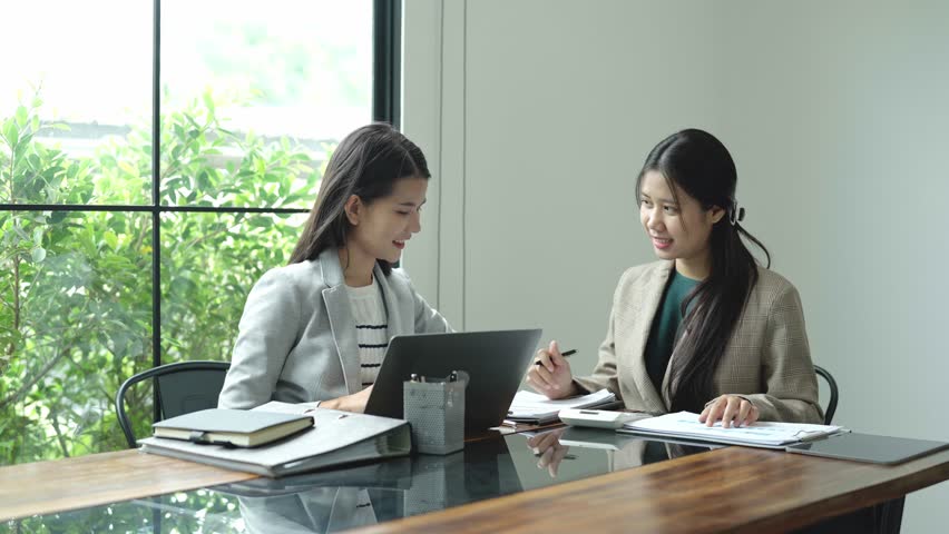 Two Asian women working together in an office.