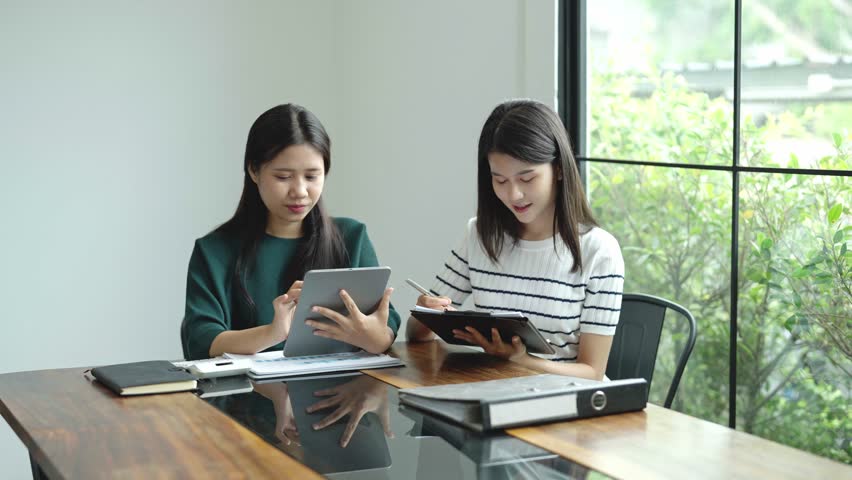 Two Asian women working together in an office.