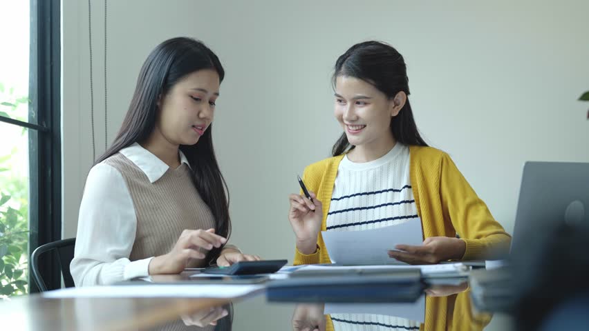 Two Asian women working together in an office.