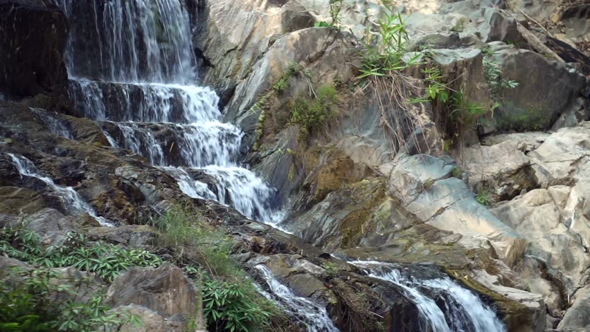 Beautiful cascading rocky waterfall flowing into a natural pool in the tropical forest.