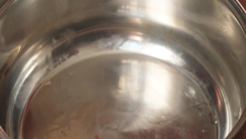 The cook puts large beef bones and pieces of raw meat into an empty metal pot. Initial stage of cooking a rich meat broth or soup base.