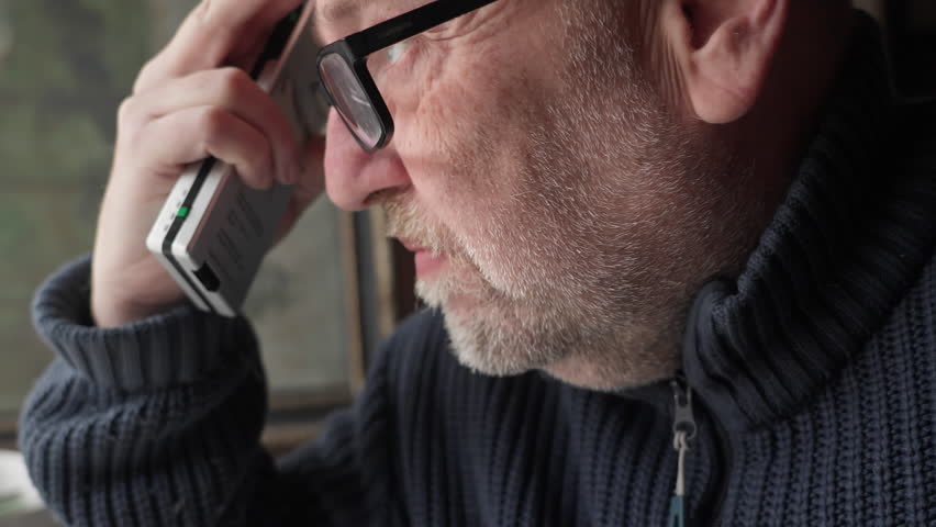 A man speaks with emotional intensity into a vintage analogue voice recorder. Cinematic profile shot for vintage communication and true crime narratives.