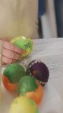 Child's hand holds colorful, painted Easter egg. Other decorated eggs rest nearby on table. Gentle, curious touch suggests festive, creative activity. Ideal for Easter crafts, family holiday projects - Powered by Shutterstock - Get 15% off with code: PIKWIZARD15