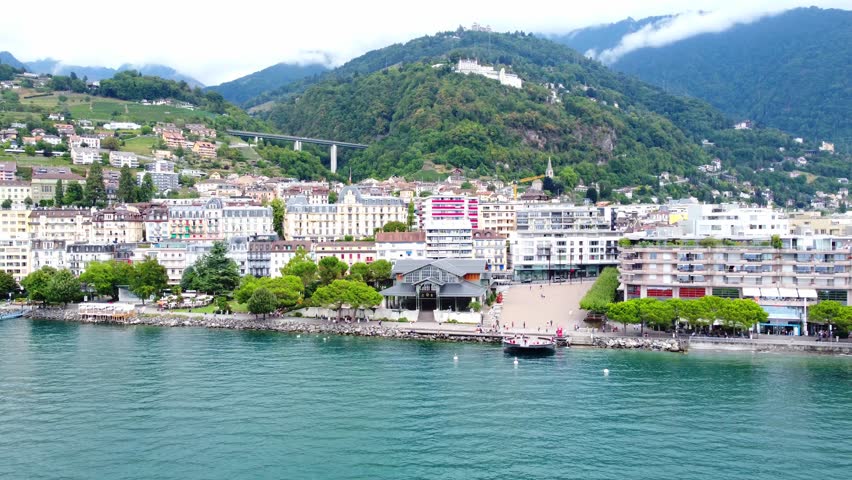 The charming Swiss town of Montreux situated at the foot of the Alpine peaks on the shores of Lake Geneva. Town panorama and the boat under the Swiss flag sets sail.