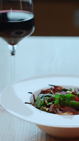 salad with arugula, meat ham and berry or hands decorating dish with strawberry