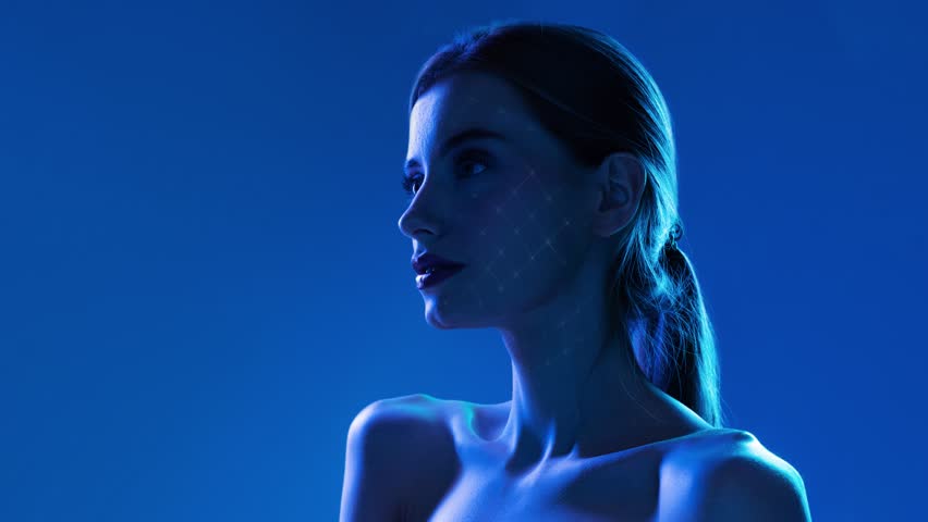 Woman face with glowing digital grid mapping under blue lighting on minimal background. Concept of advanced skincare technology, biotech beauty, anti aging innovation and premium cosmetic solutions.