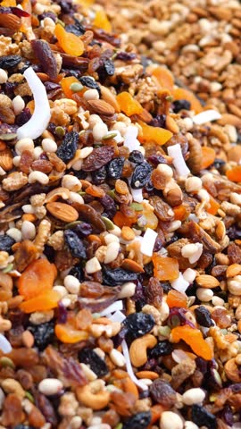A close up view of a delicious and healthy trail mix with various nuts, seeds, and dried fruits rotating, offering a vibrant and appetizing snack option